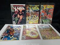 Six X-Men comic books displayed in two rows, three standing on top and three lying flat on a surface, each in protective plastic sleeves.