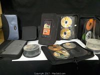 Overview of multiple CDs and DVDs along with CD/DVD cases showing Looney Tunes design and various other cases, discs stacked in spindle and loose discs