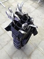 Top angled view of golf club heads inserted into black golf bag, showing several iron clubs and a putter