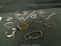 Overview of the jewelry lot spread on black fabric showing all bracelets and bangles organized together with varied styles and metals.