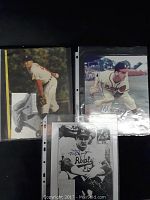 Four autographed Hall of Fame baseball player photos including Bob Lemon, Stan Coveleski, Tom Lasorda, and Warren Spahn laid out against dark background.
