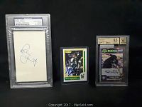 Photo showing the three cards included in the lot: Robert Yount autographed index card in PSA slab, Neil Broten signed hockey card, Steve Smith Rookie autographed and graded card in slab.