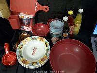 Photo of the Coca Cola miscellaneous lot showing plates, bowls, glasses, condiment bottles, and cutting board.