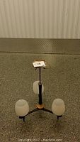 Full view of the mid century ceiling light fixture laid on the floor showing the three frosted glass shades and central column with rod and wiring.