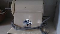Photo of Champion brand logo on the electric juicer base unit, cord coiled around it.