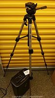 Full view of the Velbon CX44H tripod standing on the floor next to the black Omnitech shredder with power cord visible.