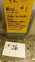 Handwritten list on a yellow paper attached to the IKEA bin listing items included: Mother Sun sticks, Soak, Lifefactory nipples, Kinetic insulator, Petit collage mobiles, Mimi Juni nipples, and butterfly CDs.
