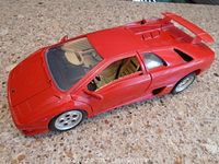 Front-side view of red Lamborghini Diablo die-cast model car showing beige interior and missing right front tire.