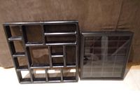 Two black display cases of different sizes and compartment layouts shown upright against a brown background.