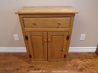 Front view of the wood cabinet showing the drawer and two doors with knob handles.