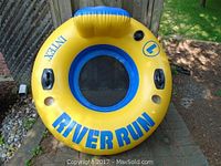 Top-down view of circular yellow and blue Intex River Run inflatable tube with mesh seat and two black cup holders opposite each other, backrest area visible.