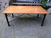 Angle view showing wood top and black metal legs with decorative curved metal support bars