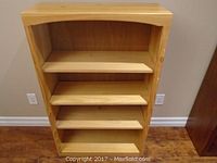 Front view of pine bookcase showing four shelves and wood grain.