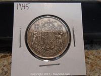 Obverse side of the 1945 Canadian 50 cents silver coin showing the detailed Canadian coat of arms and inscription.