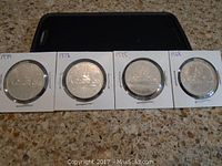 Four Canadian silver dollar coins from years 1968, 1975, 1978, and 1979, front side showing Canadian motifs.