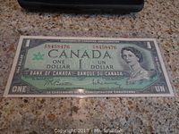 Front side of 1967 Canadian one dollar banknote showing Queen Elizabeth II portrait and serial number F8458476.