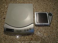 Both small scales shown side by side on a granite countertop; one larger Taylor Lithium scale and one smaller Diablo scale.