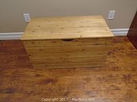 Front view of the pine chest, showing horizontal plank construction and natural wood finish.