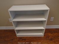 Front view of small white IKEA bookcase showing three shelves.