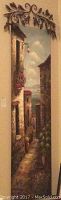 Tall oil painting of narrow alley with stone buildings, flowers, mounted with decorative metal rod.