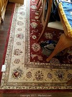 Partial view under dining table showing red field and cream border with floral design