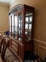 Front right angled view of oak-finished china cabinet showing glass doors and interior contents
