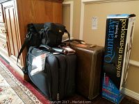 Photo showing two pieces of luggage, a camera bag, and a boxed Quantum tri-monopod tripod.