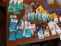 Table with multiple Super Bowl pins in original packaging, mostly blue and teal cards with mascot designs.