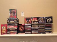 Photo shows 25 DVDs stacked, mostly movie titles and boxed sets.