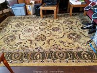 Full view of the area rug showing the floral and vine pattern along with wear marks