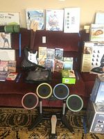 Full overview of all items including Wii games, Rock Band controllers, and consoles on a red sofa.