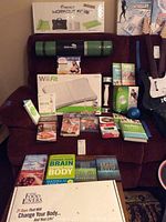 Various workout, fitness, and Wii Fit related items shown together on a red chair including Wii Fit board, exercise mat, Wii controllers, and DVDs.