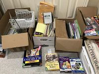 Box with white wire filing baskets and nearby cardboard boxes filled with assorted filing folders and papers, plus software boxes in front.
