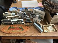Wood decorative houses and plaques along with two small blue and white plates and a basket in the background