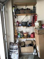 Shelf unit with bird feeders, garden pots, storage cabinet, and gas can arranged on shelves and floor