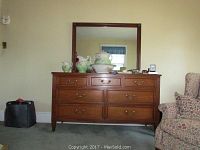 Full view of the wood dresser with mirror on top, showing the style, finish, and setting.