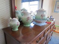 Three-piece set of vintage semi porcelain items with floral decoration on top of dresser