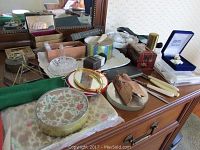Overview photo showing a variety of vintage women's items on a dresser including jewelry boxes, trays, mirrors, and grooming tools.