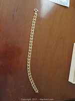 Full view of gold chain bracelet laid flat on wood surface