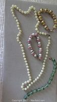 Set of three Venetian glass bracelets and one white moonstone bead necklace arranged on a neutral surface, showing variety of bead styles and colors.