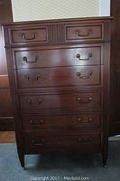 Front view of tall wooden dresser with six drawers and brass handles