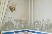 Wide view of assorted glass and crystal pieces arranged on shelves including bowls, pitchers, decanters, and candle holders