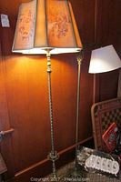 Full view of both floor lamps against a wooden wall, showing the taller floral canvas shade lamp and the shorter white shade lamp.