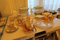Wide shot of all ceramic and glassware items on table including Noritake tea set, plates, Pickard gold pieces, and swan container