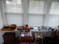 Full view of the table with wooden bowls, serving pieces, and Japanese tea set on display by window.