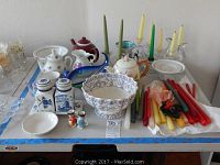 Full view of glassware and ceramic items on table with candles and salt and pepper shakers