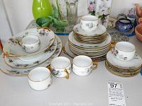 Full display of the Thomas of Bavaria handpainted china set including stacked plates, cups, saucers, and larger serving platters and bowl, all decorated with floral motifs and gold trimming.