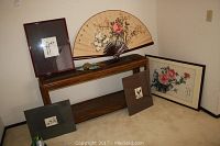 Six pieces of Asian inspired artwork arranged on two wooden stands and floor, showing framed floral paintings and a large decorative fan with flowers.