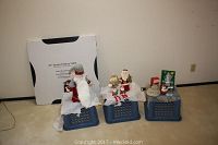 Three blue crates topped with Christmas figurines and a boxed folding table behind them.