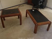 Photo showing a matching pair of tables including a square end table and a rectangular coffee table with black tile inlay and solid wood frames.